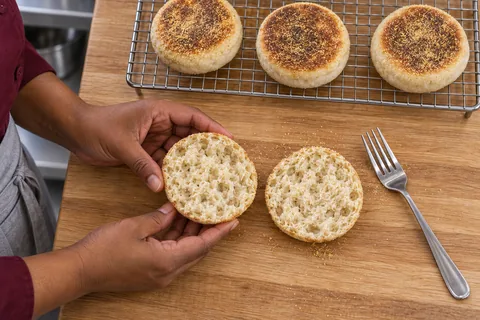 Two matching halves of one English muffin show the fork-split crumb beside three whole muffins.