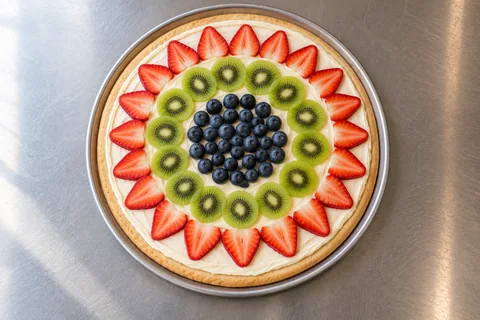 Round fruit pizza with strawberry, kiwi and blueberry rings over cream cheese icing.